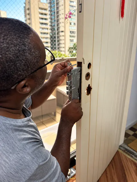 Jorge encaixando a caixa de uma fechadura de três linguetas na porta